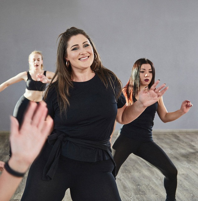 Teilnehmerinnen tanzen ausgelassen bei einer Step-Aerobic-Stunde