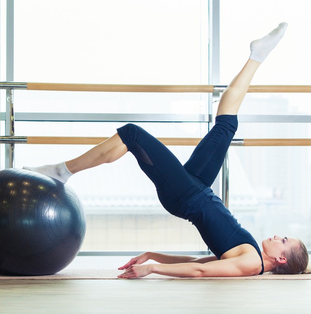 Frau bei einer Übung zur Mobilisation der Wirbelsäule mit dem Gymnastikball
