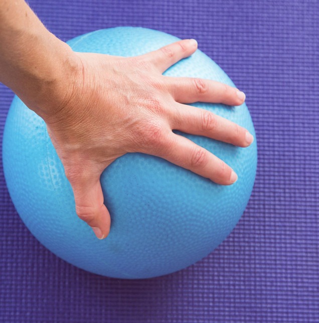Hand stützt sich auf einem Gymnastikball ab